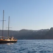 Sunset over the whitewashed village of Oia seen from the water during a Santorini boat tour, Greece